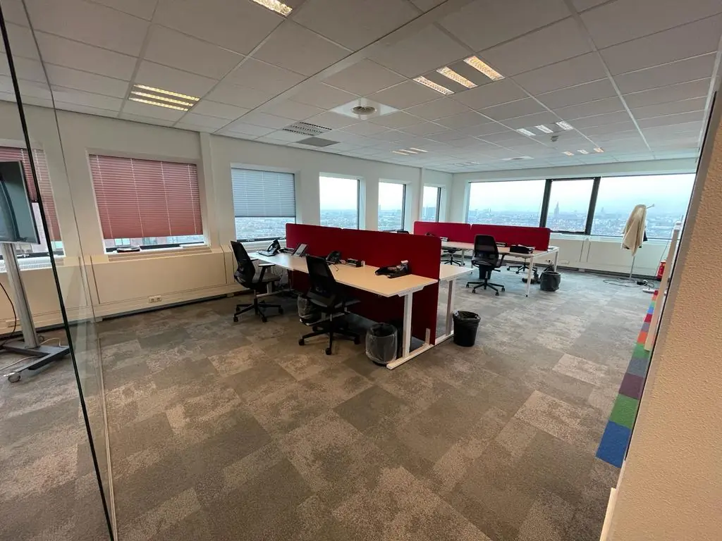 Moderne kantoorruimte aan het Johanna Westerdijkplein met bureaus, bureaustoelen en uitzicht op de stad.